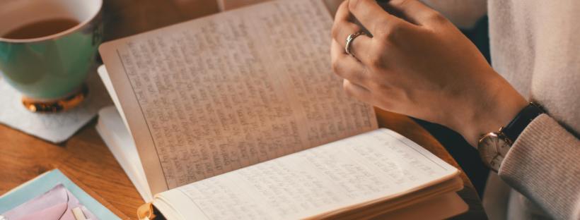 Hands hold an open journal.